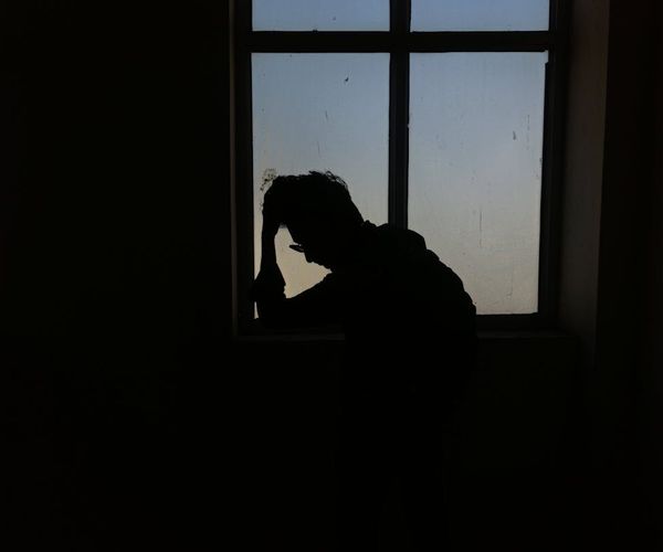 A person meditating peacefully by a window with soft light.
